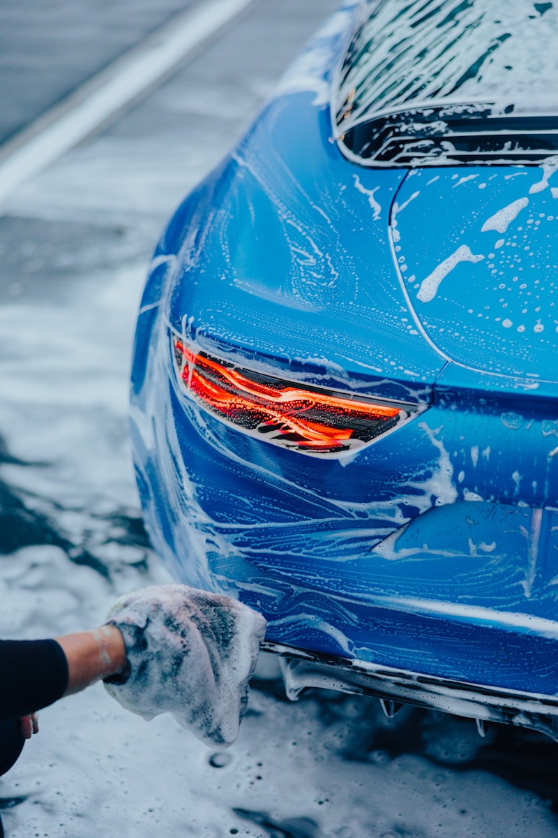 a person washing a blue car with a rag